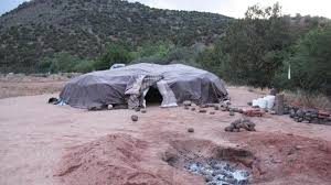 Traditional sweat lodge surrounded by natural landscape.