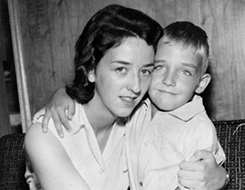 Woman hugging young boy, both smiling warmly.