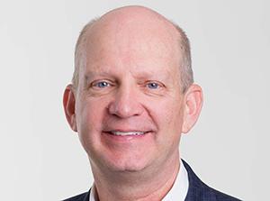 Smiling man in business attire, headshot photo.